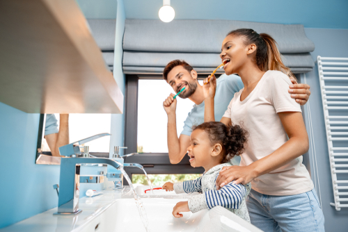 family brushing their teeth in the mirror