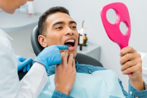 man looking at his teeth in dentist chair