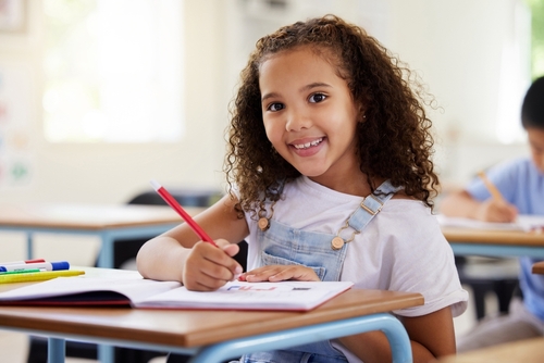 little girl smiling while sitting at school desk