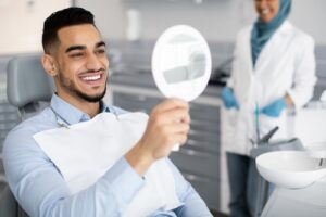 man looking at his smile in the mirror